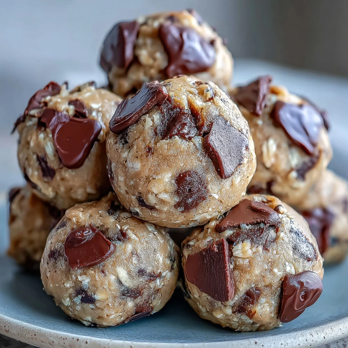 Freshly rolled Vegan Chickpea Cookie Dough Bites with dark chocolate chips on a rustic wooden board.