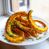 Golden-baked Cheesy Corn Ribs topped with melted cheese and fresh cilantro, served with lime wedges on a rustic platter.