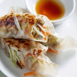 Close-up of a crispy rice paper dumpling broken open to reveal its savory vegetable and chicken filling.