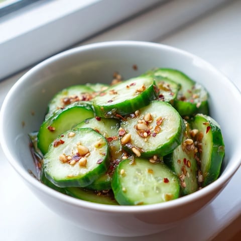 Bright green cucumber rounds glistening in a light soy-sesame dressing, garnished with sesame seeds and green onions.  