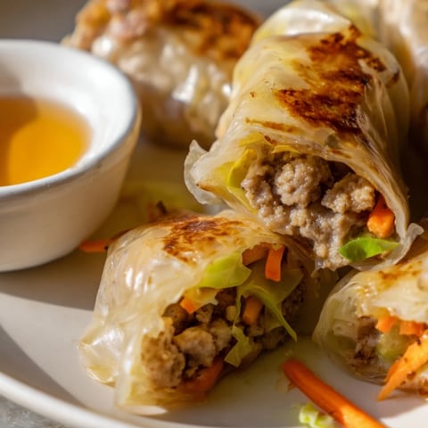Golden-brown crispy rice paper dumplings, pan-seared and served with a tangy dipping sauce on a rustic plate.