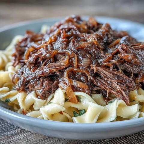 Golden egg noodles topped with tender shredded Crockpot French Onion Pot Roast and rich, caramelized onion gravy.