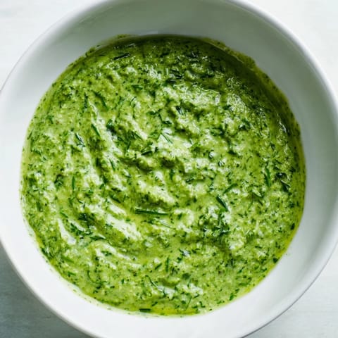 A close-up of a bowl of creamy Green Goddess Dip, perfect for dipping chips or spreading.