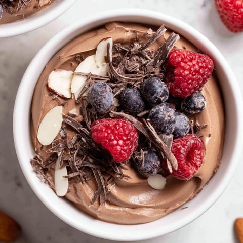 A close-up of creamy chocolate avocado mousse, rich in flavor, served with toasted almonds.