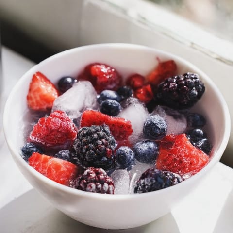 Cold, refreshing Nature’s Cereal Bowl brimming with mixed berries and coconut water over ice for a healthy breakfast.