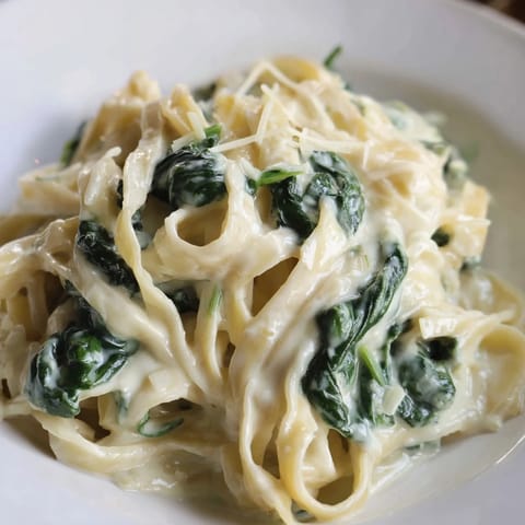 Steaming plate of Creamy Garlic Spinach Pasta garnished with fresh parsley and extra grated Parmesan, ideal for a comforting weeknight meal.