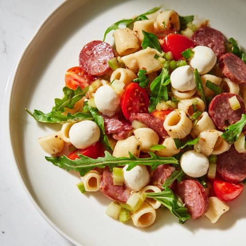 Close-up photo of Spring Antipasto Pasta Salad with colorful pickled vegetables, cherry tomatoes, and fresh herbs in a light, tangy dressing.