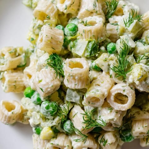 Hearty dill pickle pasta salad featuring crunchy pickles and peas in a tangy dressing.  