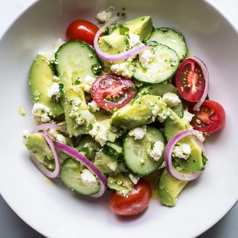 A refreshing bowl of Fresh Cucumber, Tomato, and Avocado Salad, showcasing the creamy avocado and crumbly feta.