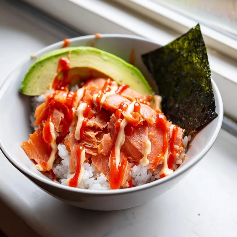 This easy Japanese-American meal features tender salmon flakes mixed with chilled rice, green onions, and sesame seeds, finished with a kick of sriracha for a quick, satisfying dinner.  