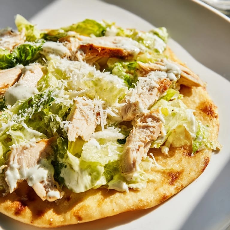Freshly grated parmesan and tangy Caesar dressing add savory flavor on warm flatbread.