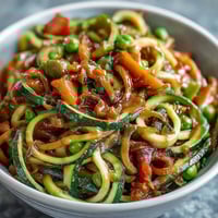 Vibrant zucchini noodles stir-fried with colorful vegetables and drizzled with creamy peanut sauce.